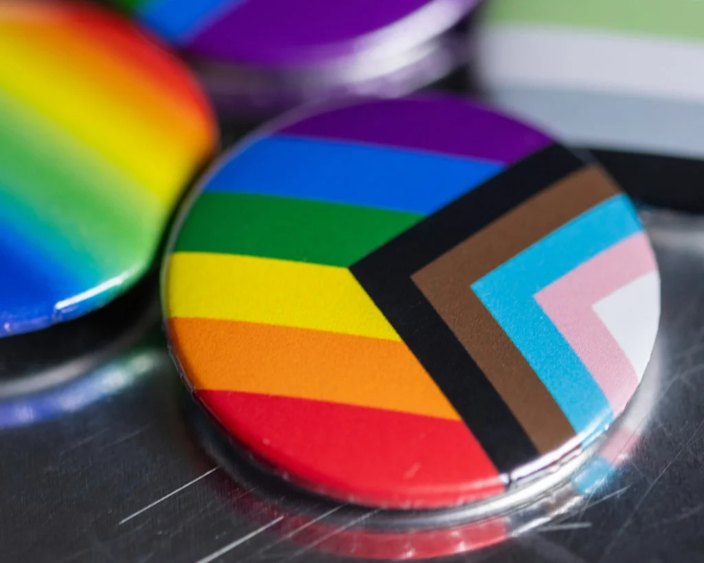 A closeup of a magnet with the progress pride flag on it