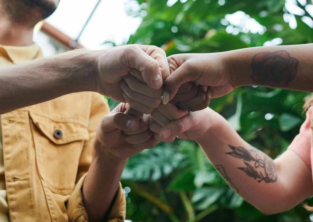 A closeup of diverse hands fist-bumping outdoors