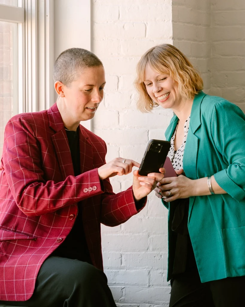 Two people in blazers looking at a phone